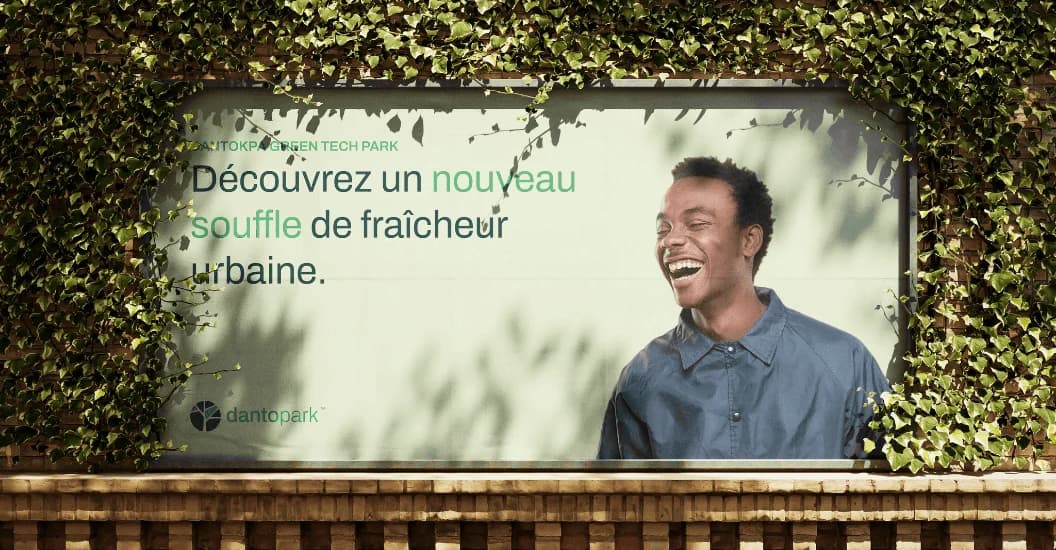 Dantopark billboard framed by ivy, reading “Découvrez un nouveau souffle de fraîcheur urbaine”